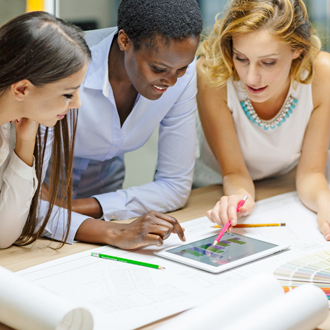 3 people reviewing a blueprint and graphs close together