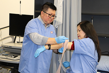 2 Personal Care Aide students practicing applying bandages