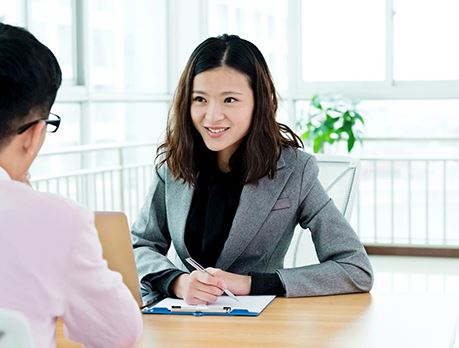 Woman in business suit takes notes during meeting with another person