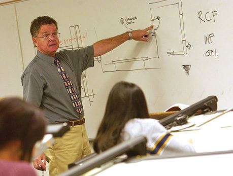 Architecture professor draws designs on a whiteboard in front of the class