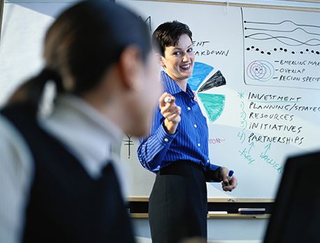 Business woman stands in front of a whiteboard with a chart on it