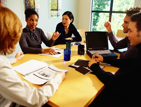 Group of business people meet around table with a laptop and graphs