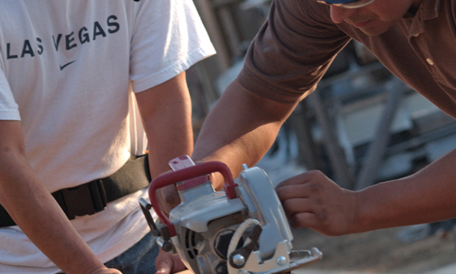 Two men use table saw to cut wood planks