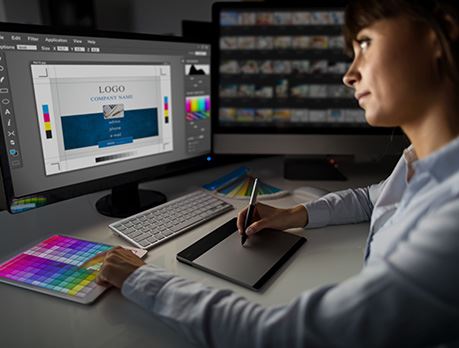 Female working at computer uses graphic drawing tablet to design business card