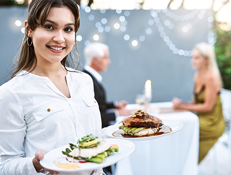 Smiling female caterer holds two bowls of soup