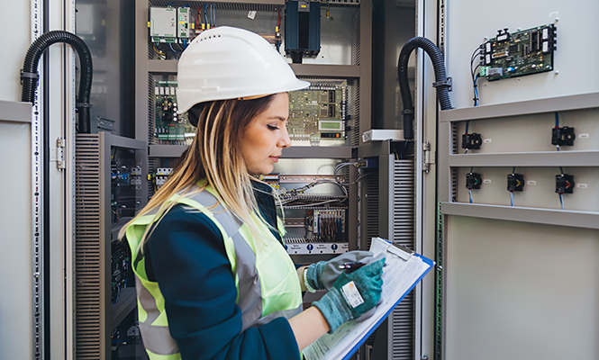 Woman wearing hard hat reviews a file during reparation of a unit