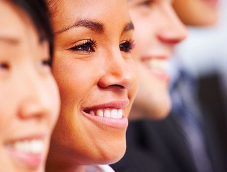 Business woman smiles close up with people on either side of her in the background