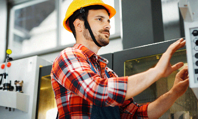 Male CNC operator works at controls