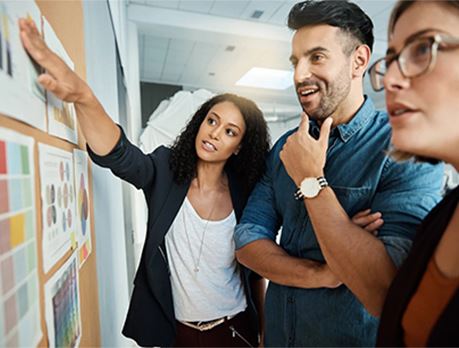 Group of professionals gathered around bulletin board review print outs with color palettes