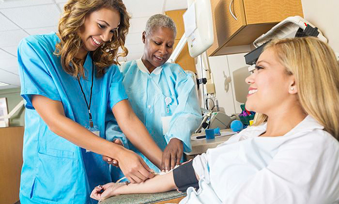 Medical assistant takes female patient's blood pressure