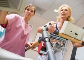 Electrocardiography technician reviews patient's results while patient walks on treadmill