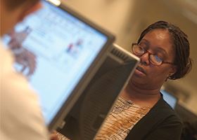 Woman works at computer with male coworker in background