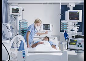 Polysomnographic technologist checks in on a sleeping patient who is monitored by medical equipment