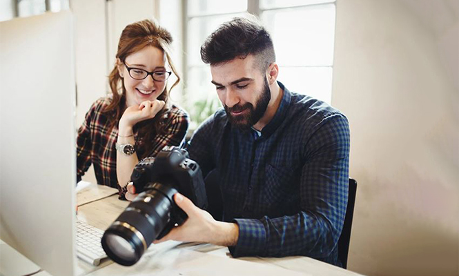 Male and female sitting together review photos on a digital camera