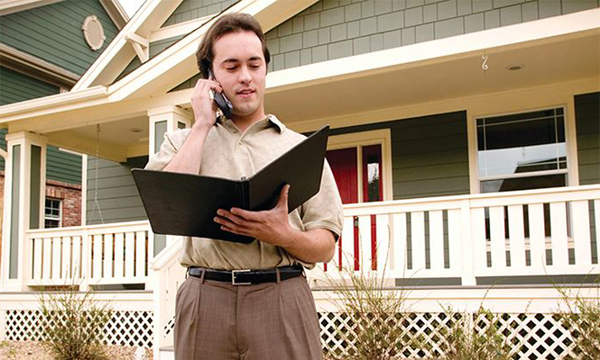 Male real estate broker talks on the phone in front of a sold house