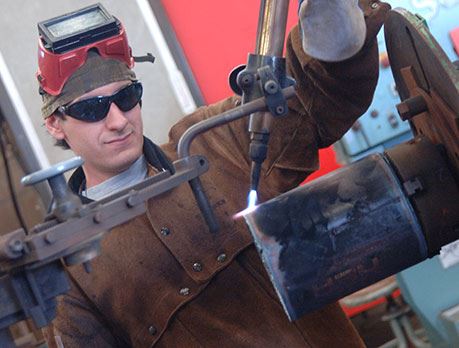 Welder in protective glasses and welding gear gets ready to weld