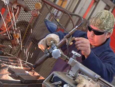 Man in protective glasses welds block of metal