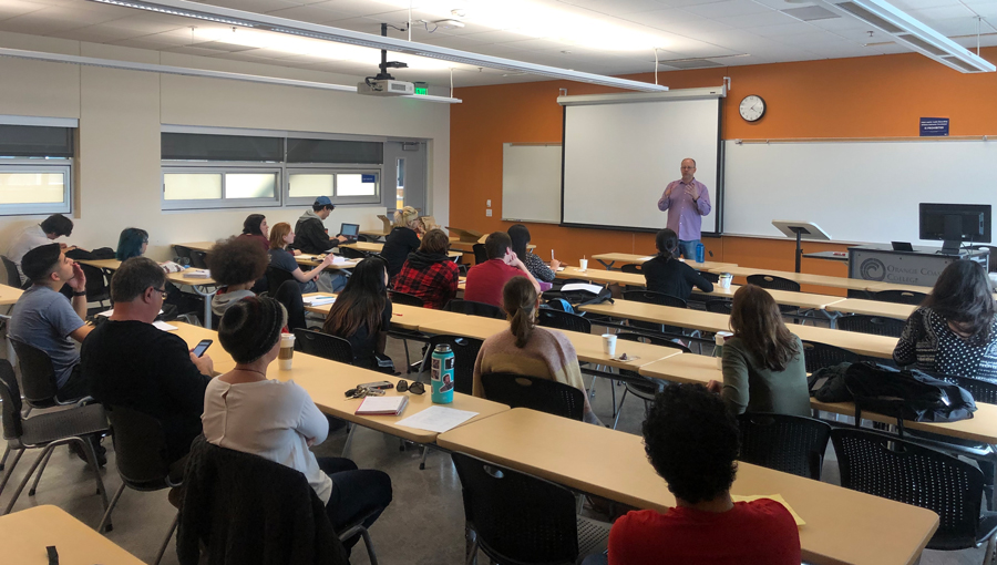 Professor Norbert Schurer lecturing in front of students and teachers taking notes