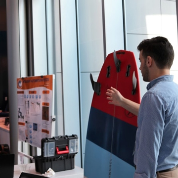 Student points to a surfboard before an audience at an exhibition