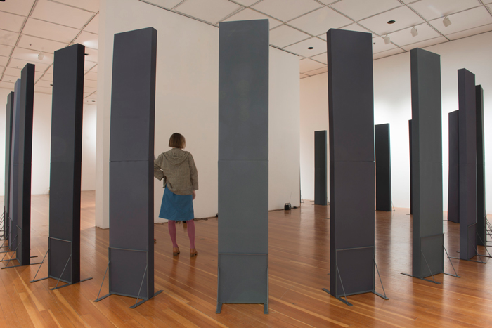 Tall black slender boarding standing around a woman in a gallery